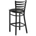 A Lancaster Table & Seating black metal ladder back bar stool with a black vinyl cushion.