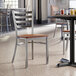 A Lancaster Table & Seating ladder back chair with a wooden seat at a table in a restaurant.