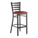 A black metal bar stool with a ladder back design and a burgundy vinyl padded seat.
