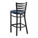 A Lancaster Table & Seating black ladder back bar stool with navy blue vinyl padded seat.