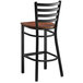 A Lancaster Table & Seating black bar stool with a wooden seat.