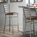 A Lancaster Table & Seating ladder back bar stool with a dark brown cushioned seat.