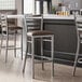 A Lancaster Table & Seating ladder back bar stool with dark brown vinyl padded seat.