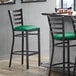 A Lancaster Table & Seating ladder back bar stool with a green vinyl padded seat.