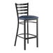 A black metal bar stool with a ladder back design and a navy blue vinyl padded seat.