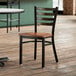 A Lancaster Table & Seating wooden chair with a distressed copper ladder back and walnut seat.