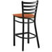 A Lancaster Table & Seating black ladder back bar stool with a cherry wood seat.