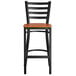 A Lancaster Table & Seating black ladder back bar stool with a cherry wood seat.