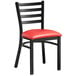 A black Lancaster Table & Seating ladder back chair with a red padded seat.