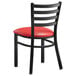 A black Lancaster Table & Seating metal chair with a red vinyl padded seat.