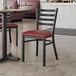 A Lancaster Table & Seating black metal chair with a burgundy cushion at a restaurant table.