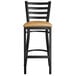 A Lancaster Table & Seating black ladder back bar stool with a light brown cushion.