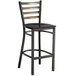 A black metal Lancaster Table & Seating bar stool with a black wood seat.