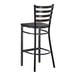 A black metal ladder back bar stool with a black wood seat and a distressed copper finish.
