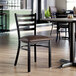 A ladder back chair with a distressed copper finish and a dark brown vinyl padded seat.