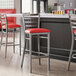 A row of Lancaster Table & Seating ladder back bar stools with red vinyl padded seats at a counter.