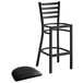 A Lancaster Table & Seating black metal ladder back bar stool with black vinyl cushion.