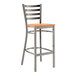 A Lancaster Table & Seating metal ladder back bar stool with a cherry wood seat.