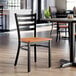 A black ladder back chair with a cherry wood seat.