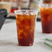 A clear 20 oz. compostable plastic cold cup filled with iced tea.