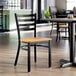 A ladder back chair with a distressed copper finish and a natural wood seat, placed in a restaurant setting.
