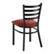 A metal ladder back chair with a distressed copper finish and a burgundy vinyl padded seat.