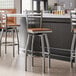 A group of Lancaster Table & Seating ladder back swivel bar stools with antique walnut wood seats at a counter.