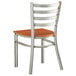 A Lancaster Table & Seating metal restaurant chair with a cherry wood seat and ladder back.