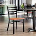 A ladder back chair with a distressed copper finish and a cherry wood seat.