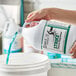 A person pouring Noble Chemical Strike All Purpose Concentrated Cleaner Degreaser into a white bucket.