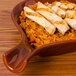 A CAC Festiware brown fry pan plate with rice and meat on a wooden table.