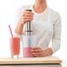 A woman using an iSi translucent silicone measuring cup to make a smoothie.