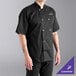 A man wearing a black Uncommon Chef short sleeve chef coat.