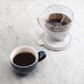 An OXO pour over coffee maker with a cup of coffee on a marble table.