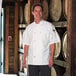 A man wearing a white Uncommon Chef short sleeve chef coat.