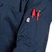 A person wearing a navy Uncommon Chef short sleeve chef coat with tools in the pocket.