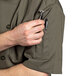 A man wearing an olive Uncommon Chef short sleeve chef coat with a pen in the pocket holding a knife.