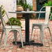 A Lancaster Table and Seating black outdoor table base with a round table and two white chairs on a brick patio.