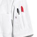 A white Uncommon Chef short sleeve chef coat with two red pens in the pocket.
