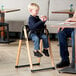 A child sitting in a Koala Stowe high chair with a black seat.