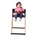 A baby sitting in a Koala Stowe high chair with a black frame.