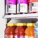 An Avantco black glass door refrigerator filled with a variety of bottled juices.