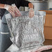 A person wrapping meat in foil using a Lavex insulated box liner.
