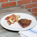 A plate of steak and potatoes on a Fiesta® Dinnerware chop plate on a table.