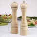 Two wooden Chef Specialties pepper mills on a table.