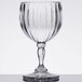 A clear GET SAN plastic wine glass with a fluted design and curved stem on a table.