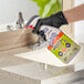 A hand in a black glove spraying SC Johnson Fantastik disinfectant on a counter.