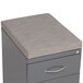 A grey file cabinet with a cushion on top.