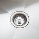 A close-up of a stainless steel sink drain on a white background.