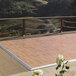 A Palmer Snyder American Plank vinyl portable dance floor with silver trim set up on a wooden deck with a white rose.